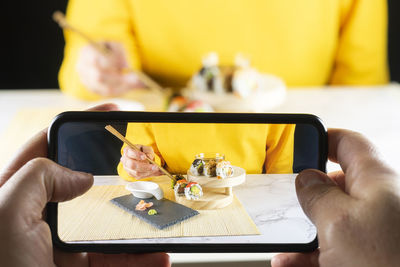 Midsection of man using mobile phone in restaurant