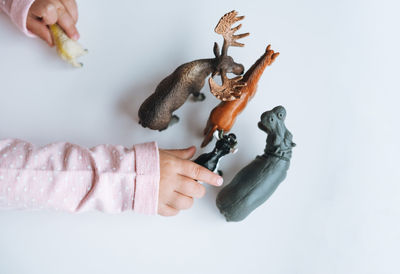 Little girl toddler playing with animal toys on table in children's room at home, view fron top