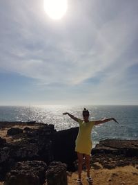 Women standing on rock by sea against sky