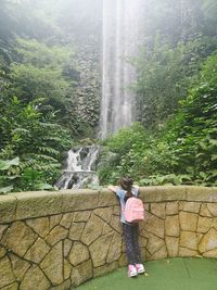 Full length of woman standing by waterfall