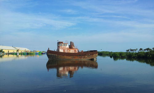 Rusty ship in lake against sky