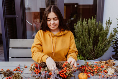 Young woman looking away while sitting on table