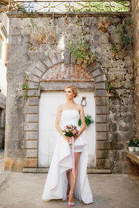 Portrait of woman standing against wall