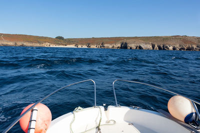 Low section of boat sailing in sea against clear blue sky