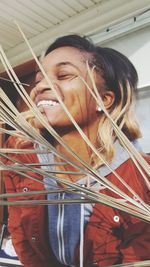 Smiling young woman with eyes closed by dry leaves