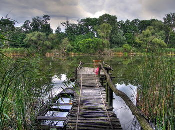 Wooden posts on river against sky