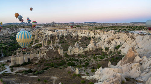 Hot air balloon flying over rocks against sky