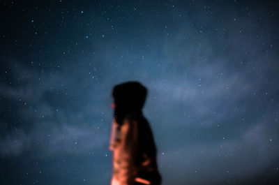 Defocused image of man standing against sky at night