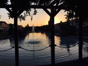 Reflection of silhouette trees in swimming pool against sky