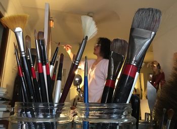 Close-up of paintbrushes against artist painting at home