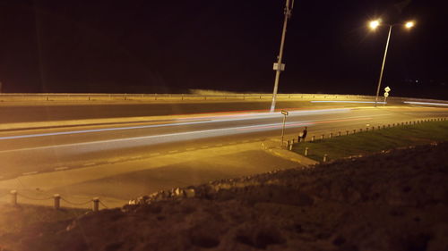 Light trails on road against sky at night