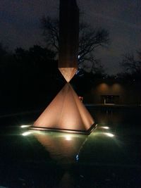 Reflection of illuminated trees in swimming pool at night