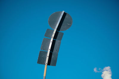 Curved road sign pole in front of blue sky