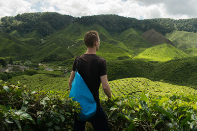 Rear view of man standing on field against sky