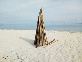 Wooden posts on beach against sky