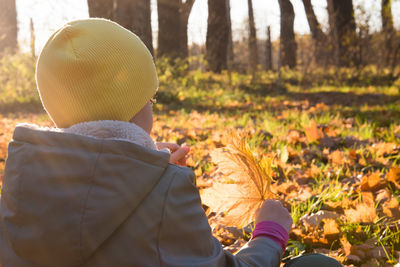 Rear view of man standing by leaves in forest