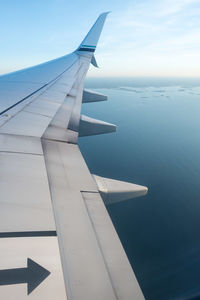 Close-up of airplane wing over sea against sky