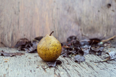 Close-up of fruits on dry leaves on table