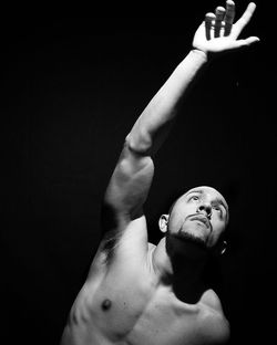 Shirtless man gesturing against black background