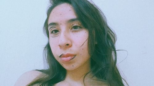 Close-up portrait of young woman against white background