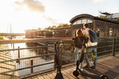 Man standing on railing by bridge against sky