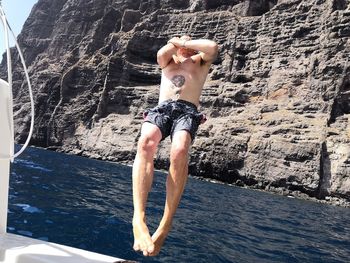 Full length of shirtless man jumping in sea