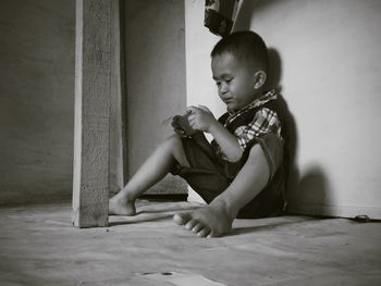 Cute boy using mobile phone while sitting on floor at home