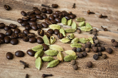 High angle view of roasted coffee beans by spices on wooden table