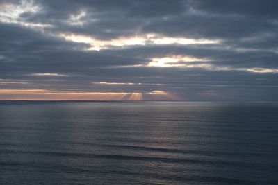 Scenic view of sea against cloudy sky during sunset