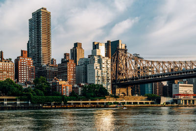 Modern buildings by river against sky in city