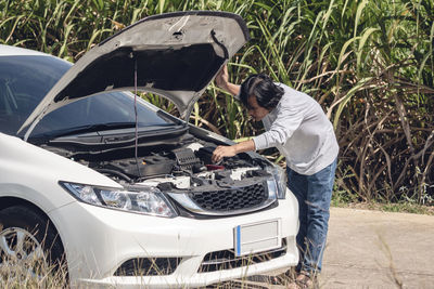 Panoramic view of man standing by car on road