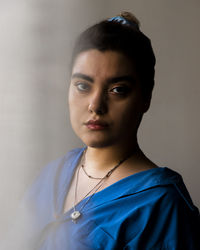 Portrait of young woman standing against wall