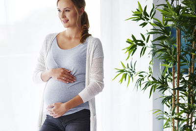 Pregnant woman touching belly at home