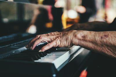 Cropped hands of senior person playing piano
