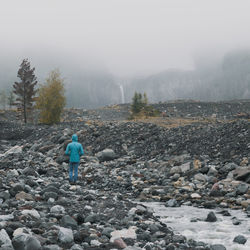 Rear view of man standing on rocks against sky