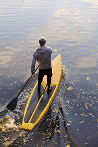 Rear view of man standing on boat in lake