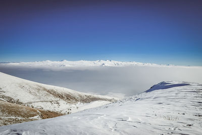 Scenic view of snowcapped mountains against clear blue sky