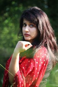 Portrait of beautiful woman holding red leaf outdoors