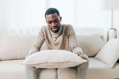 Portrait of young man using laptop while lying on sofa at home