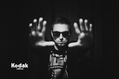 Portrait of boy wearing sunglasses standing against black background