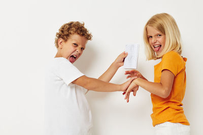 Happy siblings doing mischief against white background