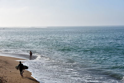 Man walking at beach against sky