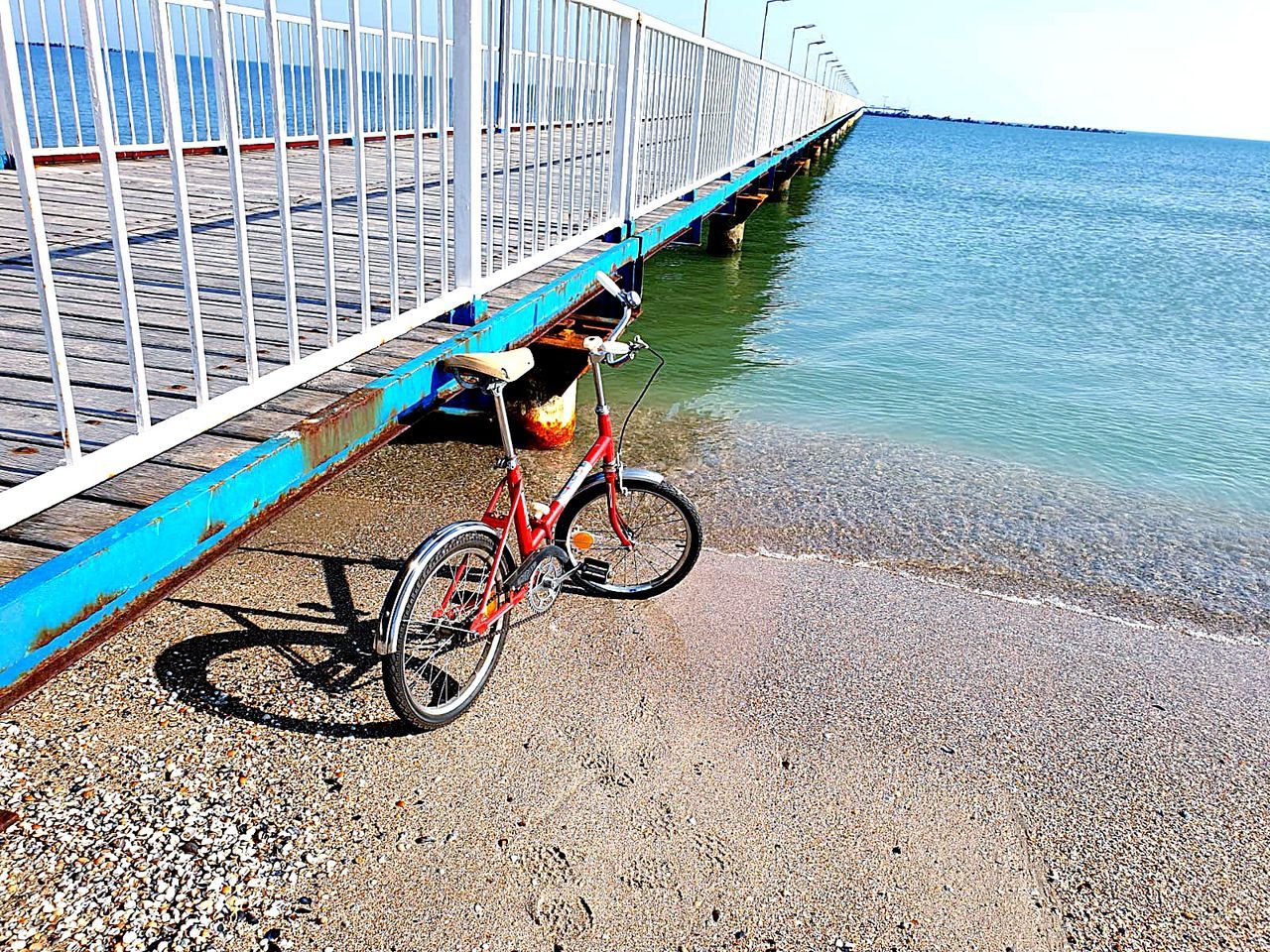 transportation, bicycle, water, mode of transportation, land vehicle, day, railing, nature, sea, no people, road, sky, beach, outdoors, the way forward, direction, land, built structure, architecture