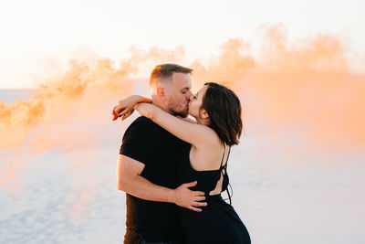 Couple standing against sea during sunset