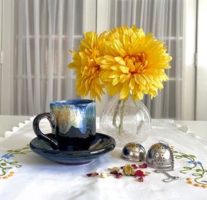 Close-up of drink on table, pottery teacup and saucer, tea , flowers