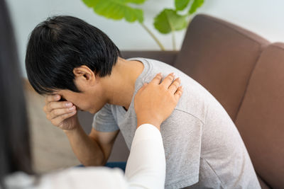 Midsection of man sitting on sofa at home