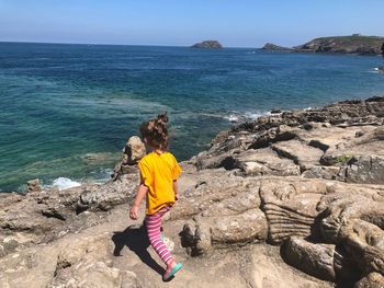 Girl on rock formations by sea