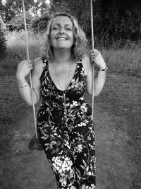 Portrait of smiling woman swinging at park