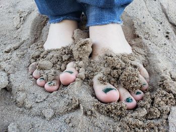Feet with green nail polish in the sand