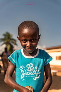 Portrait of smiling girl standing against sky during sunny day